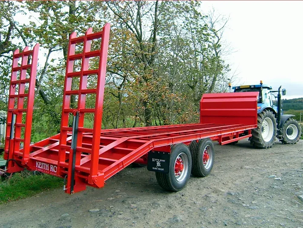 Red beavertail trailer with loading ramps behind a tractor