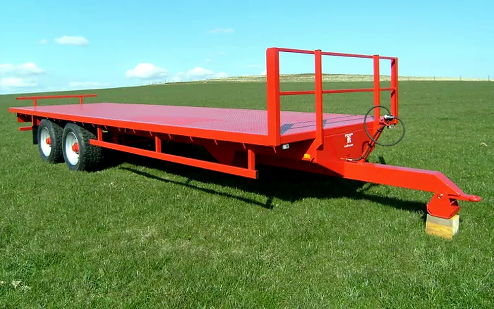 Red twin axle flat trailer with bale retainer